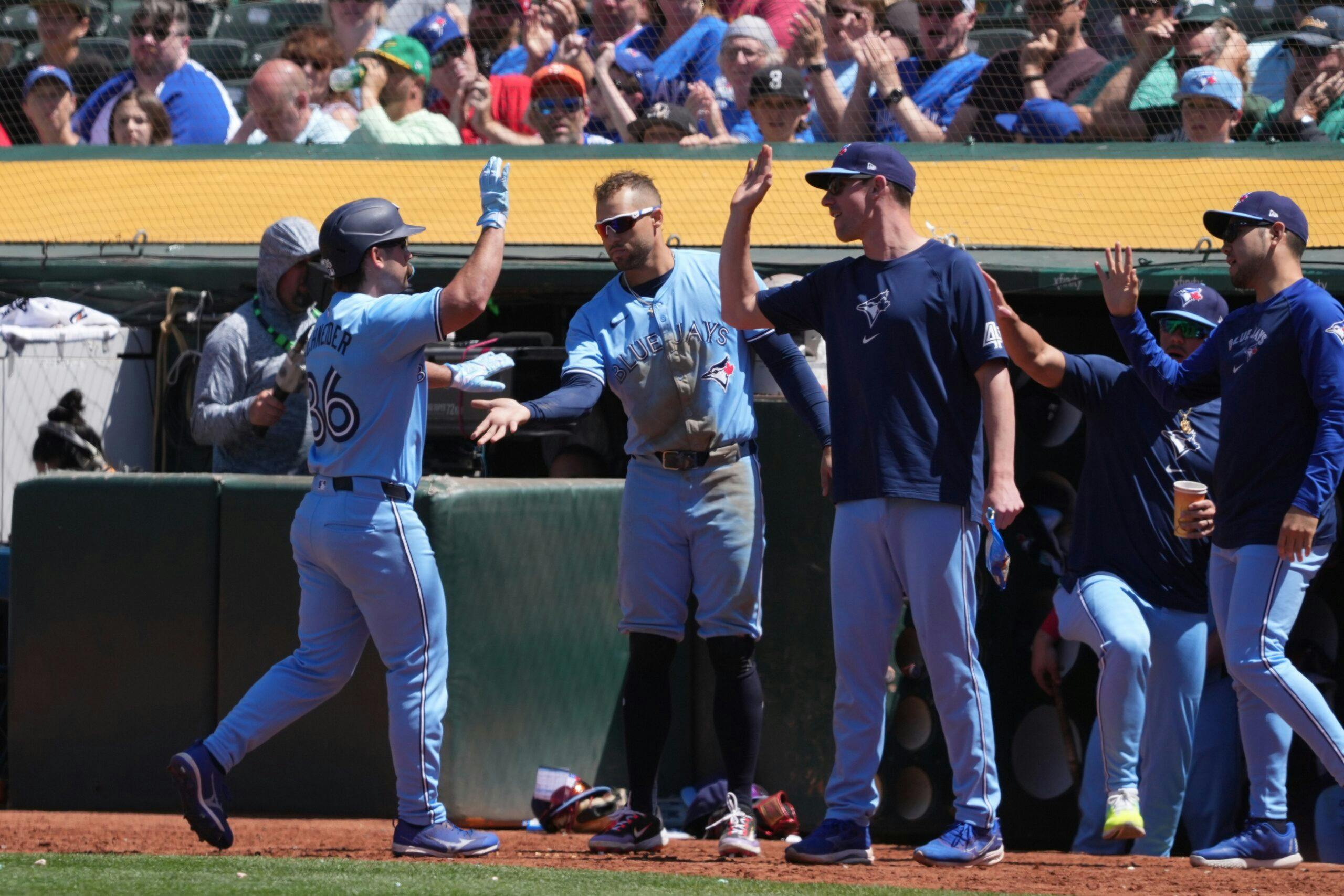 Toronto Blue Jays pinch hitter Davis Schneider (36) is congratulated by teammates after hitting an RBI-sacrifice fly against the Oakland Athletics during the eighth inning at Oakland-Alameda County Coliseum