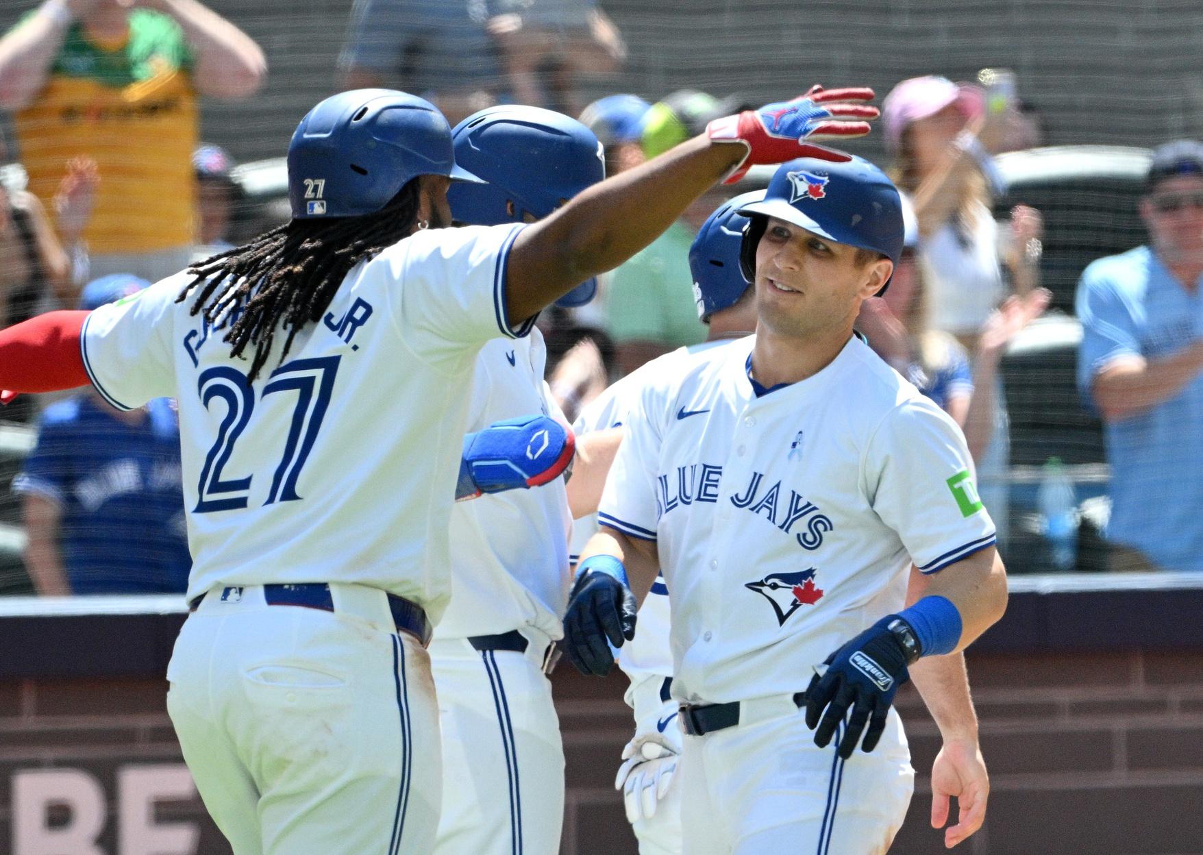 Toronto Blue Jays center fielder Daulton Varsho (25) is greeted by team mates at home plate after hitting a grand slam home run against the Cleveland Guardians in the fifth inning at Rogers Centre