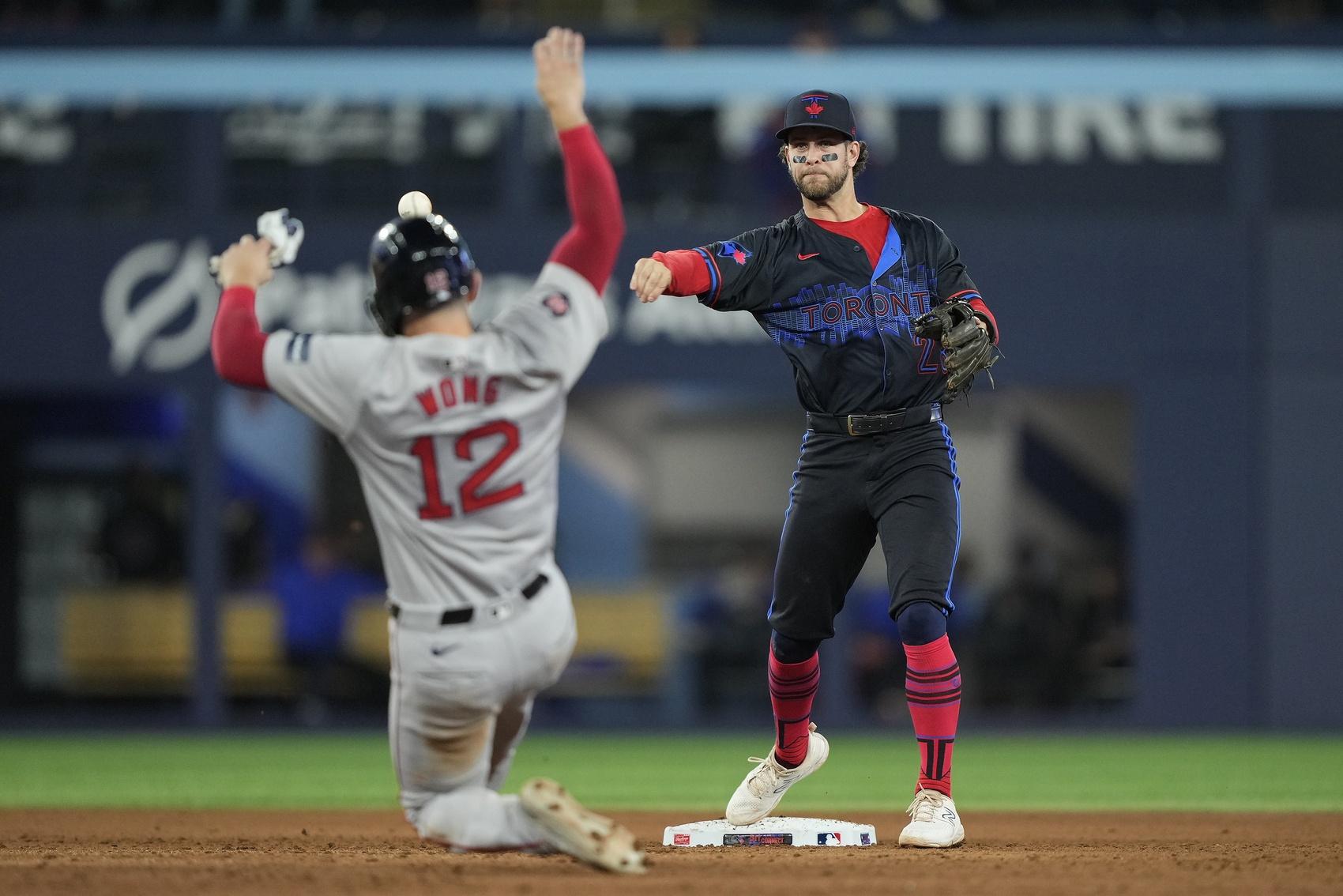 Toronto Blue Jays shortstop Ernie Clement (28) turns a double play against Boston Red Sox catcher Connor Wong (12) during the fifth inning at Rogers Centre.