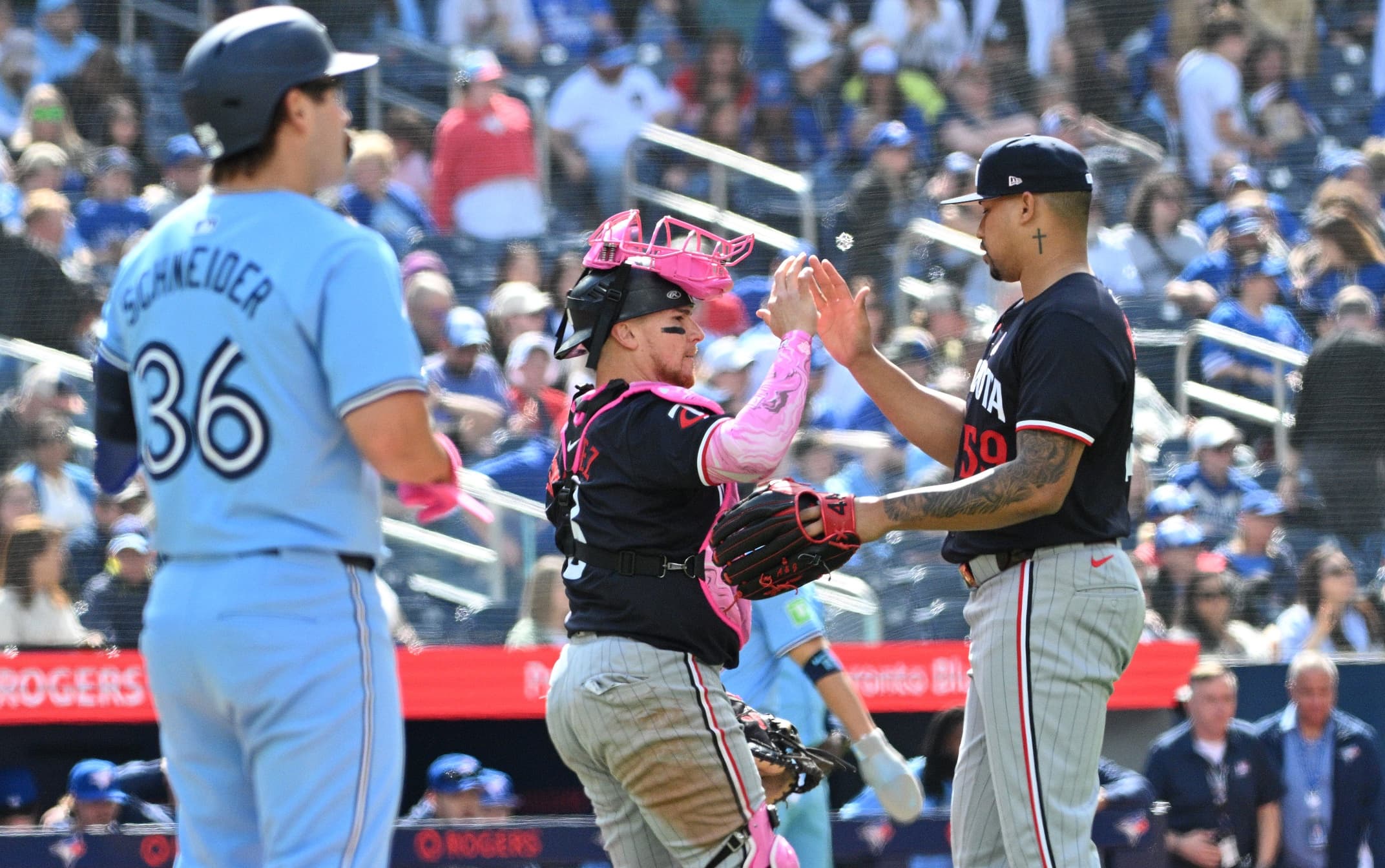 Minnesota Twins relief pitcher Jhoan Duran (59) and catcher Christian Vazquez (8) celebrate a win as Toronto Blue Jays left fielder Davis Schneider (36) looks on at Rogers Centre.