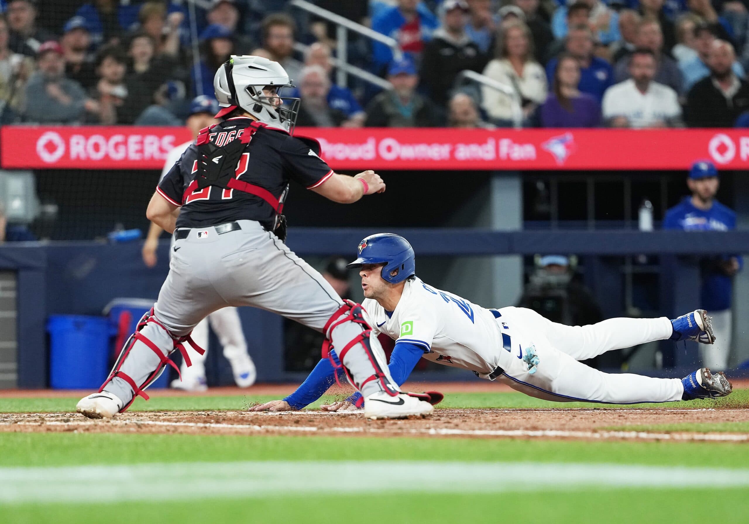 Toronto Blue Jays pinch hitter Ernie Clement (22) slides into home plate ahead of the tag from Cleveland Guardians catcher Austin Hedges (27) during the fifth inning at Rogers Centre