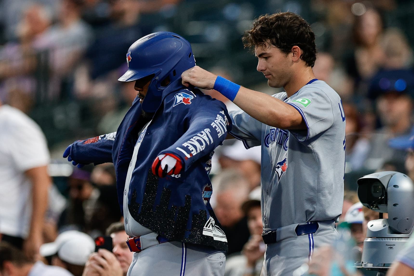 Toronto Blue Jays left fielder Joey Loperfido (10) puts the celebration jacket on first baseman Vladimir Guerrero Jr. (27) after his solo home run in the sixth inning against the Colorado Rockies at Coors Field.