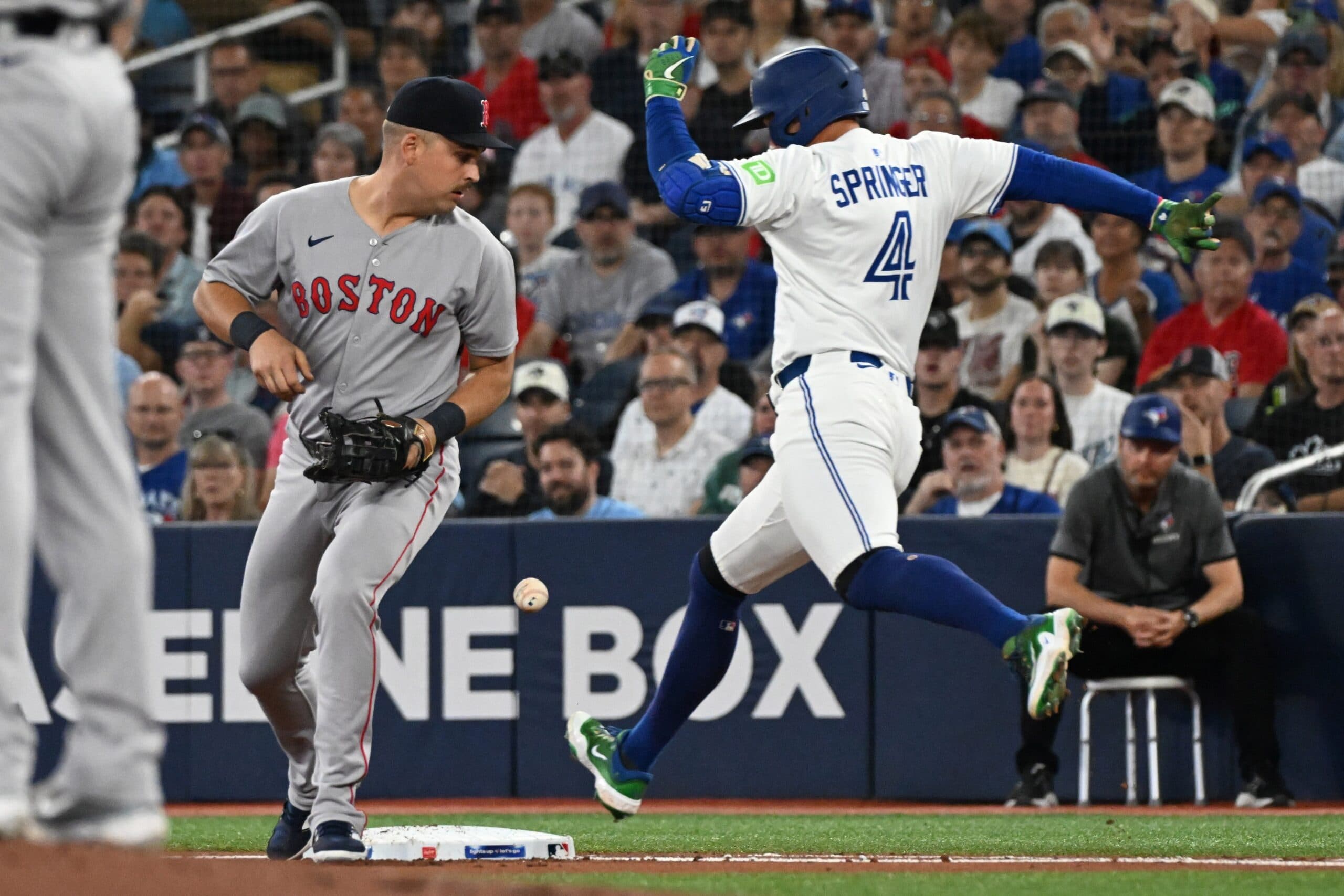 Toronto Blue Jays designated hitter George Springer (4) is safe at first after Boston Red Sox first baseman Nathaniel Lowe (37) drops a throw in the first inning at Rogers Centre.