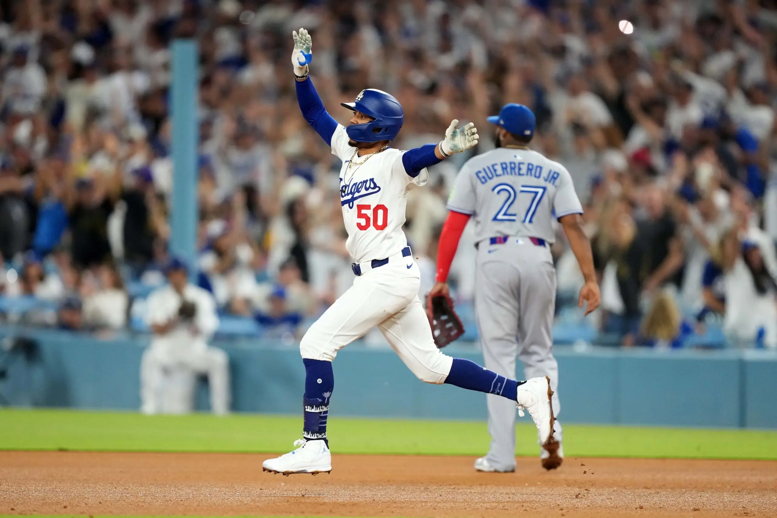 Los Angeles Dodgers shortstop Mookie Betts (50) runs the bases after hitting a home run in the fifth inning as Toronto Blue Jays first baseman Vladimir Guerrero Jr. (27) reacts at Dodger Stadium.